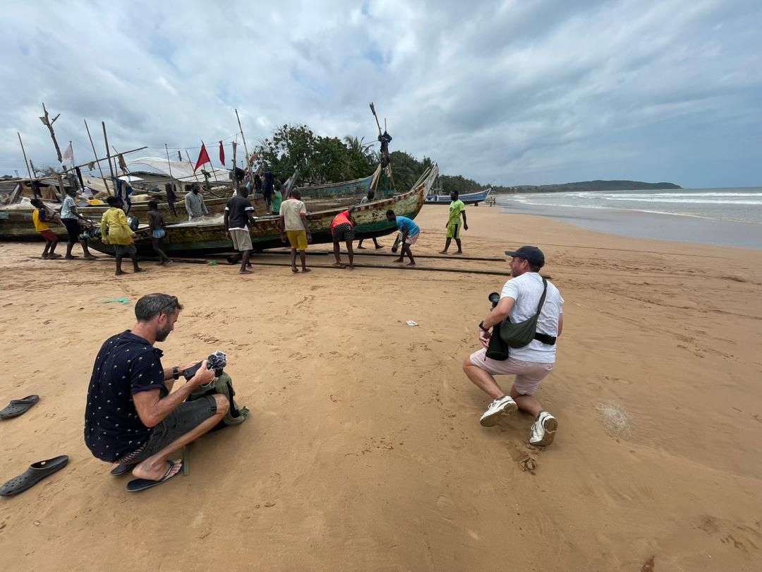 Crew filming the community hauling a canoe ashore on Dixcove beach