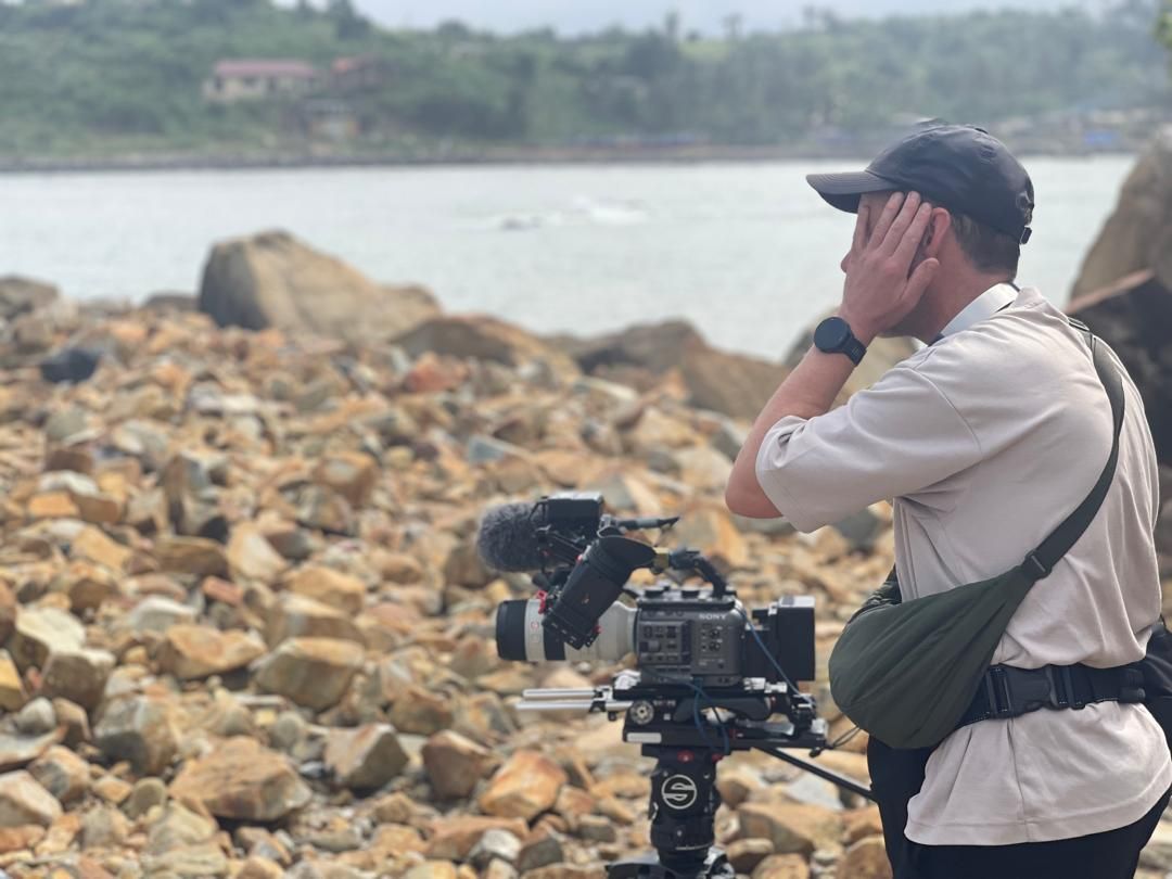 Crew filming the canoe fishing expedition from the rocky Dixcove coastline