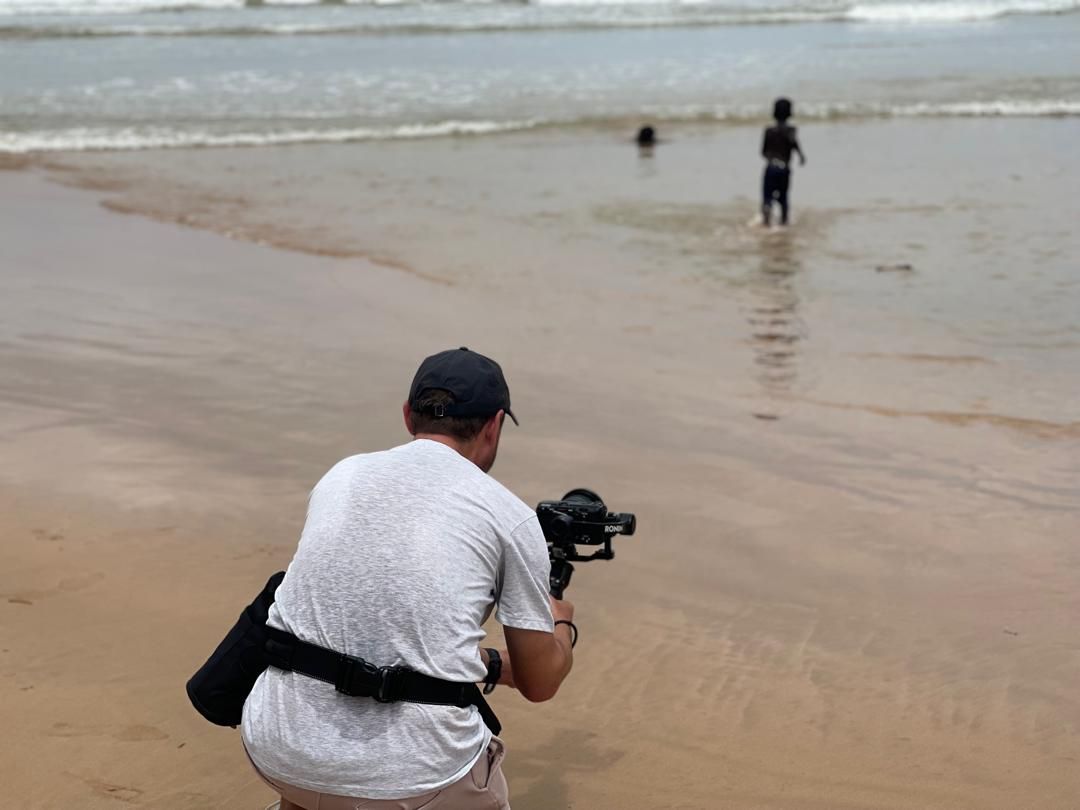 Crew filming children wading into the sea at Dixcove with a gimbal rig