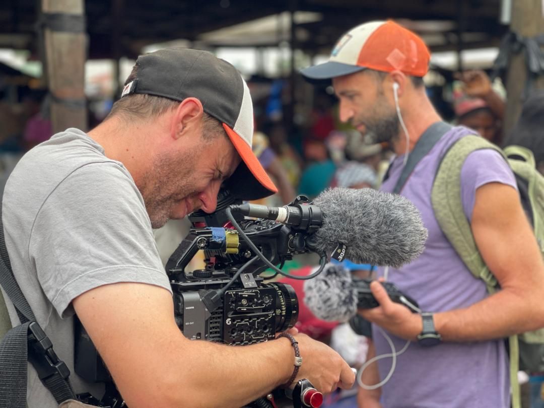 Crew filming and recording sound at a busy market near Dixcove