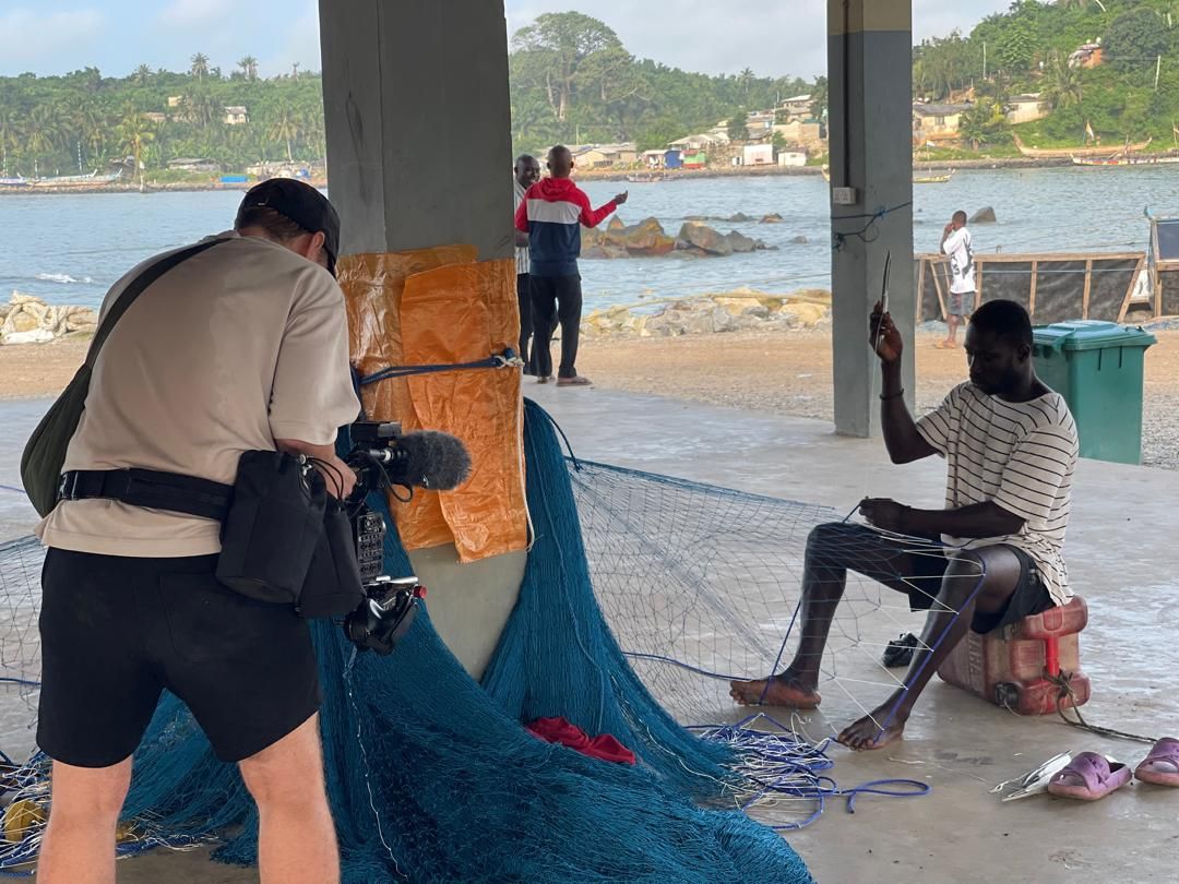 A fisherman repairing nets on the Dixcove coastline