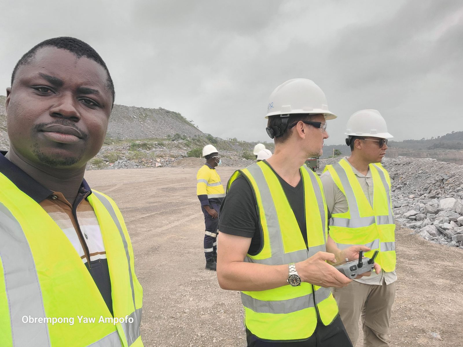 Crew preparing a drone for an aerial survey at a mine site, holding a DJI controller